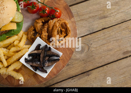 Aufwand für die Zwiebel Ring, Hamburger und Pommes Frites auf Schneidebrett Stockfoto