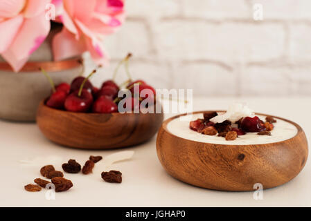 Haferflocken mit Joghurt und Obst. Kirschen, Rosinen und Kokos-Chips. Übernachtung Frühstück. Gesunde Ernährung-Konzept. Fitness-Stimmung-Ernährung. Sommerlicht Sna Stockfoto