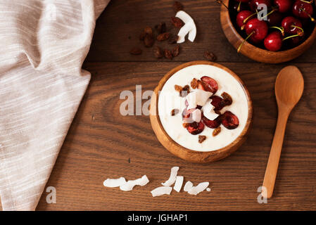 Haferflocken mit Joghurt und Obst. Kirschen, Rosinen und Kokos-Chips. Übernachtung Frühstück. Gesunde Ernährung-Konzept. Fitness-Stimmung-Ernährung. Sommerlicht Sna Stockfoto