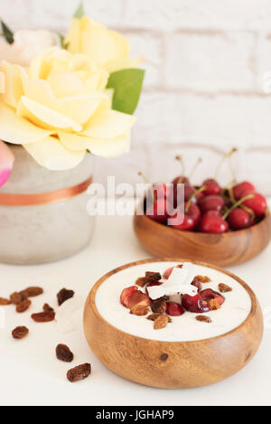 Haferflocken mit Joghurt und Obst. Kirschen, Rosinen und Kokos-Chips. Übernachtung Frühstück. Gesunde Ernährung-Konzept. Fitness-Stimmung-Ernährung. Sommerlicht Sna Stockfoto