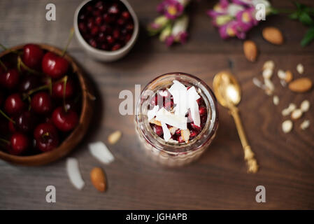Über Nacht Chia Pudding mit Chia-Samen, Hafer, Granatapfel und Kokos-Chips. Gesundes Frühstück-Konzept. Dunklen Hintergrund. Gesunder Lifestyle-Konzept. Co Stockfoto