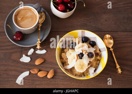 Mandelmilch Quinoa mit frischen Früchten, Kirschen und Kaffee. Gesundes Frühstück, Lifestyle-Konzept. Ansicht von oben. Dunklem Holz. Fitness-Stimmung-Ernährung. Stockfoto