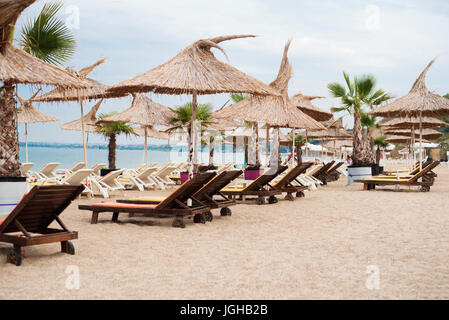 Strand Stuhl mit Stroh Sonnenschirme und Sonnenliegen. Schwarzmeerküste In Bulgarien. Ferienkonzept Stockfoto