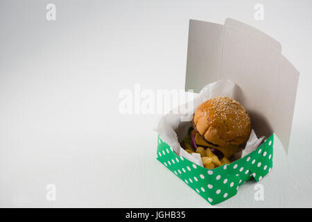 Cheeseburger mit Pommes frites im Feld auf Tisch Stockfoto