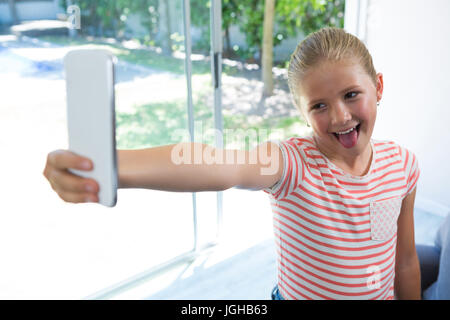 Playgul Giirl unter Selfie stehend durch Fenster zu Hause Stockfoto