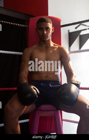 Porträt von zuversichtlich Mann sitzt im Boxring im Fitness-studio Stockfoto