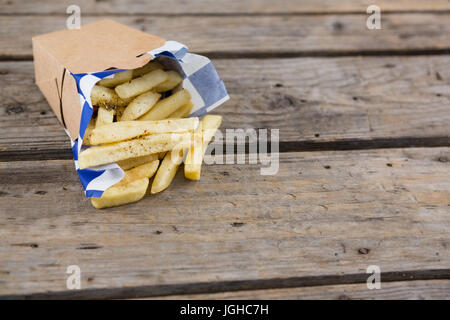 Nahaufnahme von Pommes frites im Container auf Holztisch Stockfoto