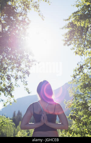 Rückansicht des Frau reverse Gebet Pose im Wald an einem sonnigen Tag zu tun Stockfoto
