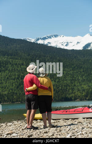 Rückansicht des reifes Paar stehen am Seeufer gegen Berge Stockfoto