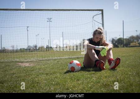 Voller Länge des müde weiblichen Fußballer entspannend auf Spielfeld Stockfoto