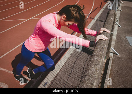 Voller Länge Sportlerin durch Geländer auf der Laufstrecke Stockfoto