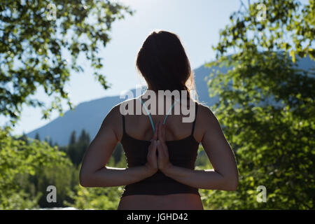 Rückansicht des Frau reverse Gebet Pose im Wald an einem sonnigen Tag zu tun Stockfoto