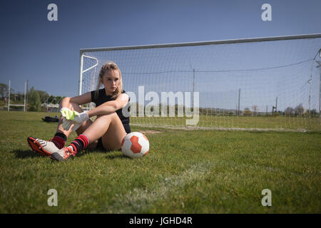 Voller Länge des weiblichen Fußballer Entspannung durch Torpfosten auf Spielfeld Stockfoto