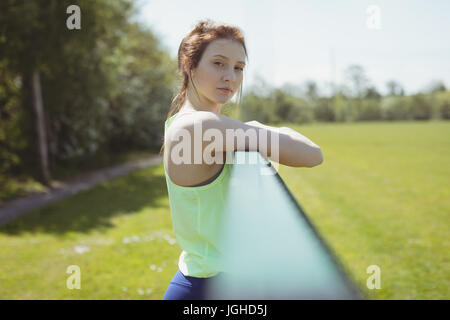 Porträt der jungen Sportlerin durch Geländer an sonnigen Tag stehen Stockfoto