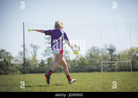 Rückseite Blick voller Länge der Spielerin Fußballspielen auf Feld gegen Himmel Stockfoto