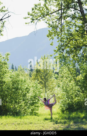 Schöne Frau, die Yoga in einem grünen Wald an einem sonnigen Tag machen Stockfoto