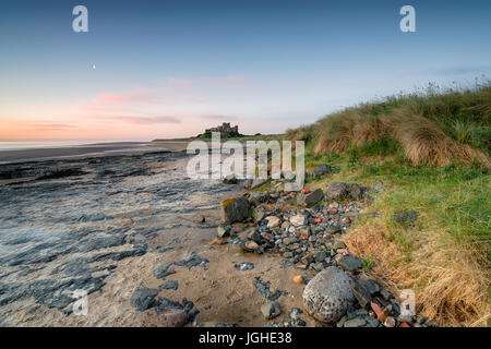 Morgendämmerung über Bamburgh Castle in Northumberland Küste Stockfoto