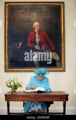 Königin Elizabeth II. unterzeichnet das Gästebuch, darunter ein Porträt von König George III, während eines Besuchs in der Royal Society of Edinburgh, wo sie Royal Medaillen Professor Peter Boyle und Professor Tessa Holyoake vorgestellt. Stockfoto