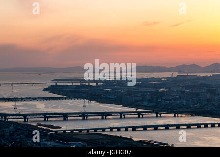 Die Mündung des Fluss Yodogawa in Osaka City bei Sonnenuntergang. Jenseits der Berge, die Küste und die akashi Kaikyo suspension Braut. Orange Sky. Stockfoto