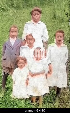 Porträt von einer afrikanischen amerikanischen Mutter und ihre fünf Kinder auf einem grasbewachsenen Hügel stehend, alle Mädchen sind in hellen Kleidern und der junge ist in einem dunklen Anzug, 1920. Hinweis: Bild wurde digital eingefärbt wurde mit einem modernen Verfahren. Farben können Zeit ungenau sein. Stockfoto