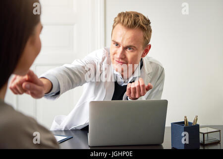 Spa und Beauty professional Mann am Computer sitzen und berührend Chin von jungen weiblichen Kunden. Stockfoto