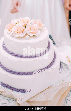 Leckere Hochzeitstorte, verziert mit Rosen und lila Sauerrahm. Stockfoto