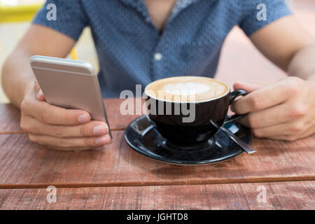 Nahaufnahme des Menschen im Café im freien SMS auf Handy Stockfoto