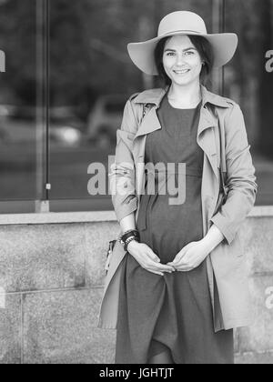 Schwarz-weiß Foto eines schwanger elegante Frau. Portrait von einem schwangeren Mädchen in einen Hut Stockfoto