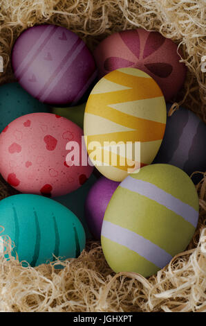 Erhöhten Blick auf lackierten und gemusterten Eiern, gruppiert und getrocknete Gras geschachtelt. Stockfoto