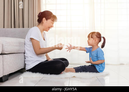 Asiatische chinesische Mutter und Tochter spielen Stein-Schere-Papier in das Wohnzimmer zu Hause. Stockfoto