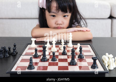 Müde chinesische kleine Asiatin spielt Schach im Wohnzimmer zu Hause Stockfoto