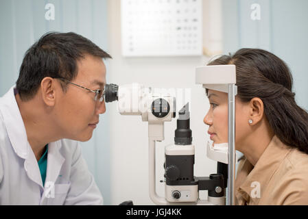 Asiatischen Arzt bei der Arbeit während der Sehkraft Examen zur erwachsenen Frau im Krankenhaus. Stockfoto