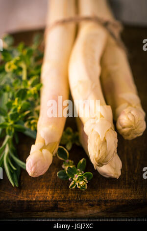 Vertikale Foto mit verklebten Haufen weißer Spargel. Köstliches Gemüse liegt auf dunkel Vintage Holz Schneidebrett mit braun und grün er Stockfoto