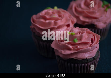 Schokoladentörtchen mit rosa Buttercreme und Pistazien Stockfoto