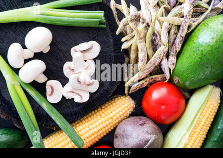 Viel frisches Gemüse auf schwarzem Hintergrund aus Holz Stockfoto