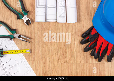 Rollen von Diagrammen und elektrische Konstruktionszeichnungen, blau Schutzhelm mit Handschuhen und Arbeitsgeräte, Zubehör für Ingenieur/in, kopieren Raum f Stockfoto