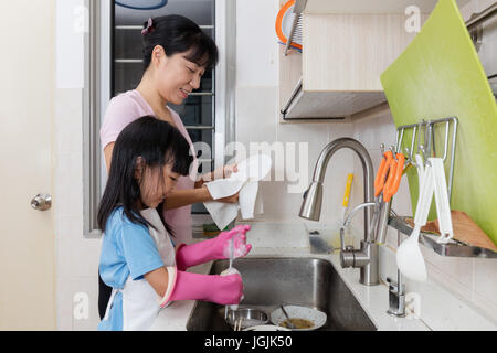 Asiatische chinesische Mädchen hilft Mutter abwaschen in der Küche zu Hause Stockfoto