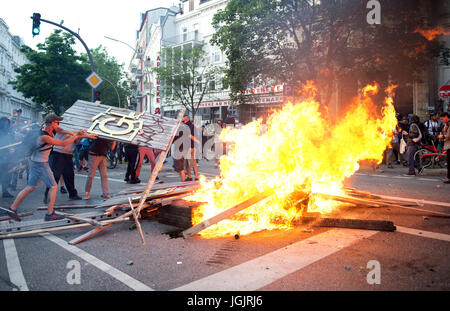 Hamburg, Deutschland. 7. Juli 2017. Aktivisten werfen Holz auf eine brennende Barrikade im Stadtteil Schanzenviertel in Hamburg, Deutschland, 7. Juli 2017. Die Regierungschefs der G20-Gruppe von Ländern treffen sich am 7. / 8. Juli 2017 in Hamburg. Foto: Daniel Bockwoldt/Dpa/Alamy Live News Stockfoto