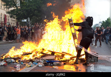 Hamburg, Deutschland. 7. Juli 2017. Aktivisten werfen Holz auf eine brennende Barrikade im Stadtteil Schanzenviertel in Hamburg, Deutschland, 7. Juli 2017. Die Regierungschefs der G20-Gruppe von Ländern treffen sich am 7. / 8. Juli 2017 in Hamburg. Foto: Daniel Bockwoldt/Dpa/Alamy Live News Stockfoto