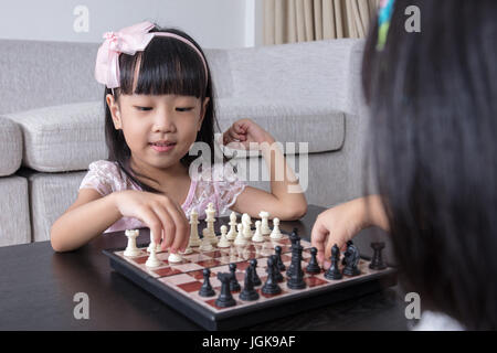 Asiatische chinesische kleinen Schwestern spielen Schach zusammen in das Wohnzimmer zu Hause. Stockfoto