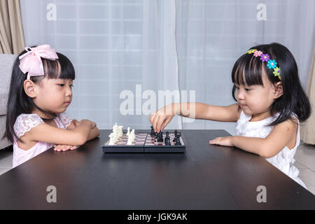 Asiatische chinesische kleinen Schwestern spielen Schach zusammen in das Wohnzimmer zu Hause. Stockfoto