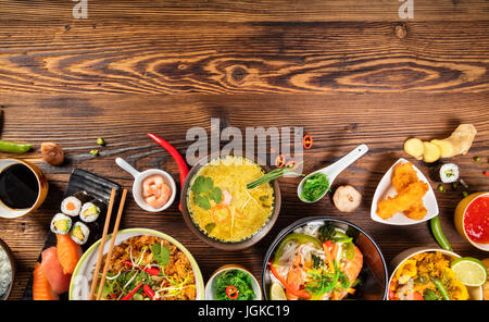 Asiatische Lebensmittel-Tabelle mit verschiedenen Arten von chinesisches Essen, Nudeln, Huhn, Schweinefleisch, Rindfleisch, Reis, Frühlingsrollen, Sushi, Garnelen und viele andere. Serviert auf alten woo Stockfoto