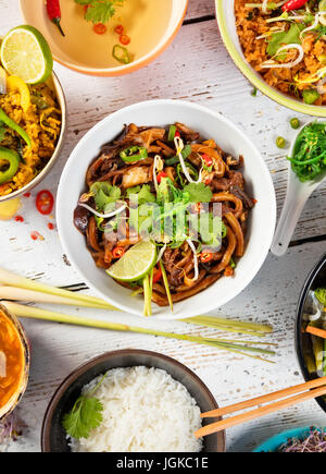Asiatische Lebensmittel-Tabelle mit verschiedenen Arten von chinesisches Essen, Nudeln, Huhn, Schweinefleisch, Rindfleisch, Reis und viele andere. Serviert auf alten Holztisch, Ansicht von oben. Stockfoto