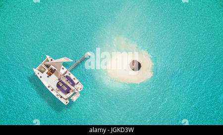 Kleine Sandinsel mit Regenschirm und Katamaran, Konzept von Entspannung und Sommerurlaub am Strand. Stockfoto