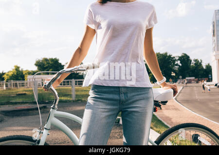 Abgeschnitten Bild einer Frau in Jeans und ein T-shirt mit dem Fahrrad in den Park, Nahaufnahme Stockfoto