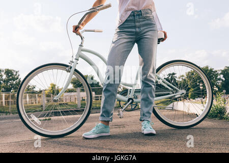 Abgeschnitten Bild einer Frau in Jeans mit dem Fahrrad in den Park, Nahaufnahme Stockfoto