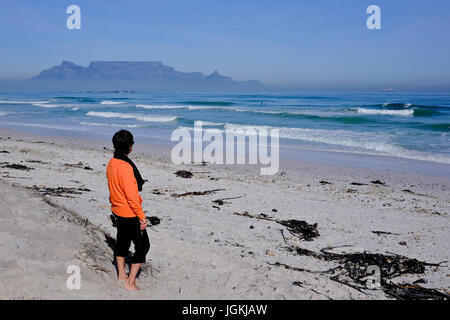 Cape Town, Südafrika. Ein Tourist Uhren Surfer eine Welle am frühen Morgen am Strand von Bloubergstrand mit dem Tafelberg im Hintergrund zu fangen. Stockfoto