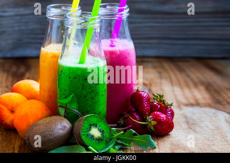 Frische Smoothies in Flaschen in drei Farben: grün mit Spinat und Kiwi, Rosa mit Erdbeeren, orange mit Aprikosen, gesunde Entgiftung Smoothies Stockfoto