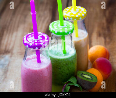 Frische Smoothies in Flaschen in drei Farben: grün mit Spinat und Kiwi, Rosa mit Erdbeeren, orange mit Aprikosen, gesunde Entgiftung Smoothies Stockfoto