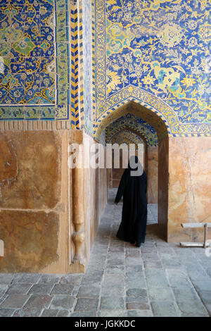 Eine Frau im Tschador geht durch einen Bogen in der königlichen Moschee in Isfahan, Iran Stockfoto